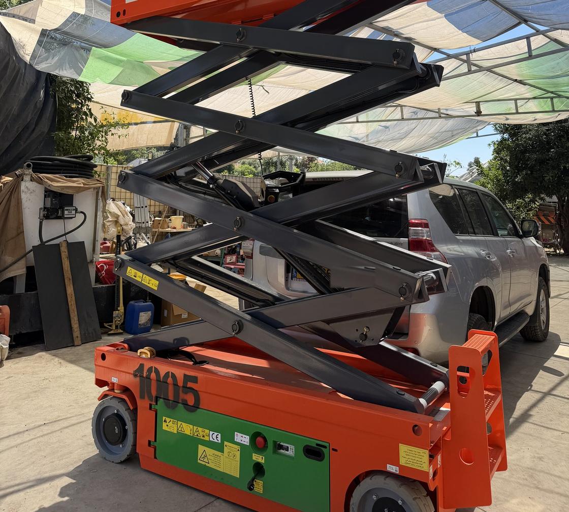 במת מספריים Dingli JCPT1008AC מורמת במגרש של רקיע, מספריים פתוחות מעל הבסיס